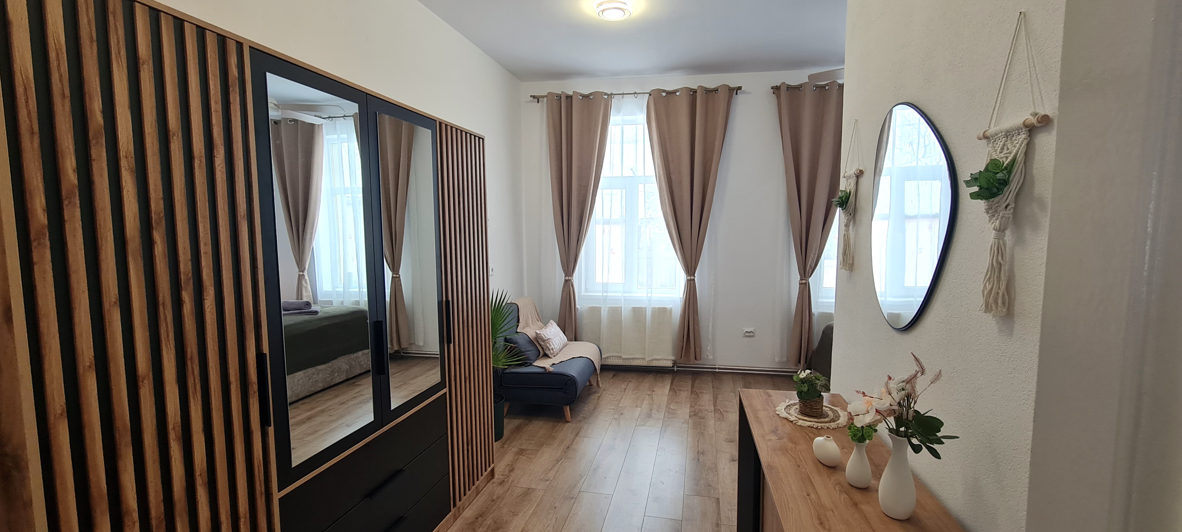 Vedere spre dormitor și zona de relaxare cu dulap și oglindă la Casa Turcu Guest